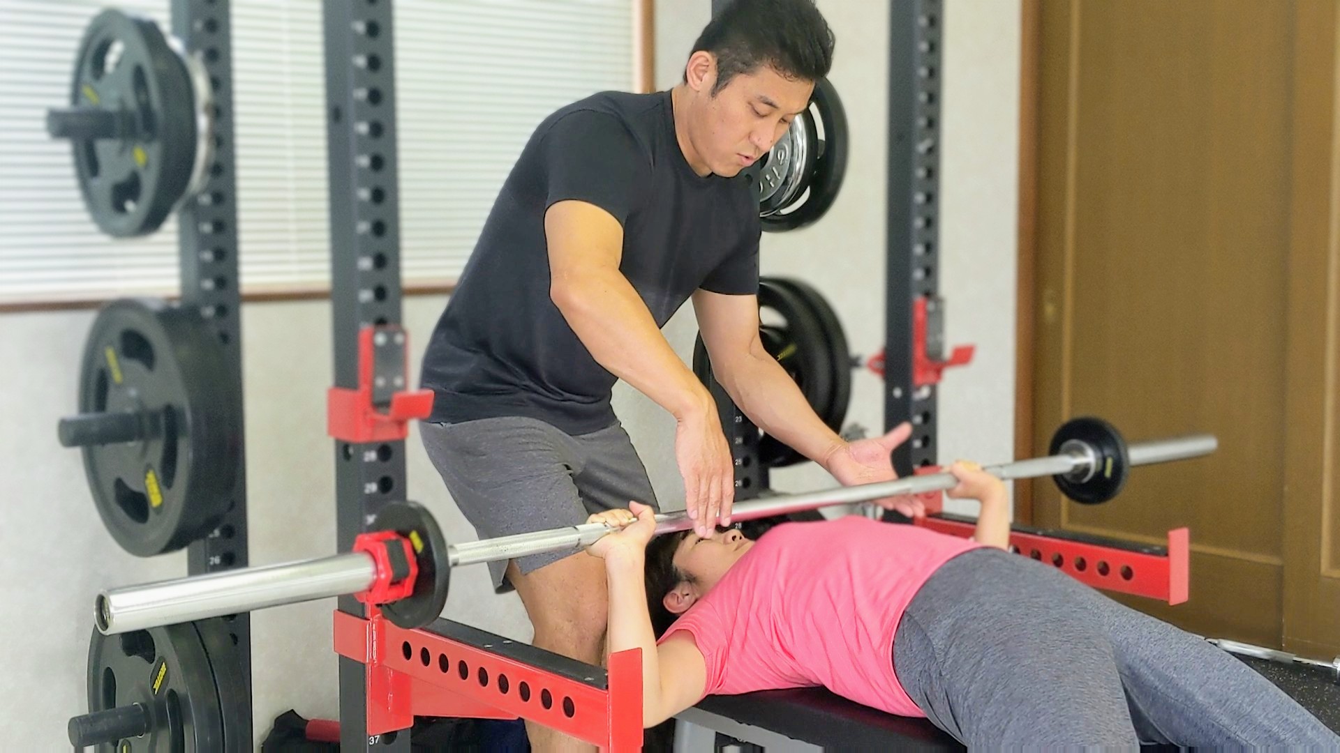 トレーナーがベンチプレスを補助している様子